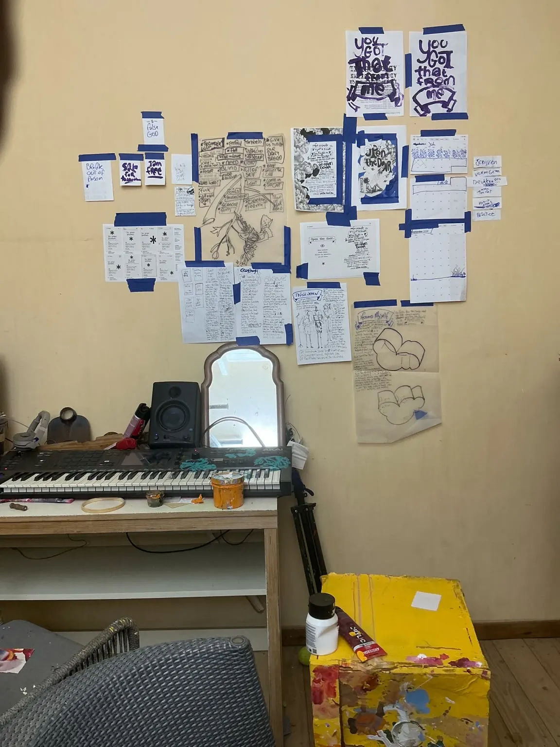 Muur in het atelier van Francis Sling met gedichten, schetsen en kalenders, vastgezet met blauwe tape, boven een keyboard.